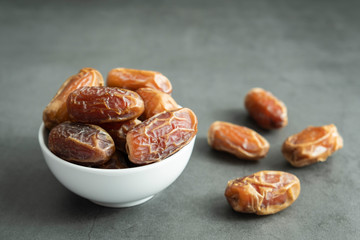 Raw date fruit ready to eat in porcelain bowl on concrete background. Traditional, delicious and healthy ramadan food.