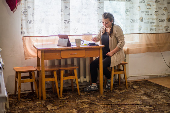 A young girl sits at home in self-isolation and works remotely at home, with finance charts. Communicates via video connection.