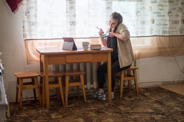 A young girl sits at home in self-isolation and works remotely at home, with finance charts. Communicates via video connection.