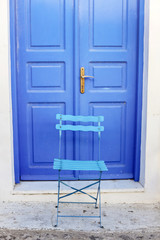 A blue wooden chair stands against a blue door