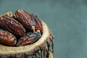 Raw date fruit ready to eat in wooden bowl on concrete background. Traditional, delicious and...