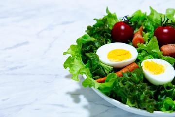 Tasty fresh mix vegetable salad on white dish and wooden plate.