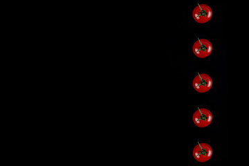 Cherry tomatoes isolated on a black background, top view