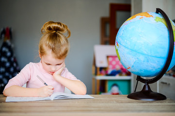 Back to School. Kid doing homework, sitting on the table, reading books near globe. Distance education concept