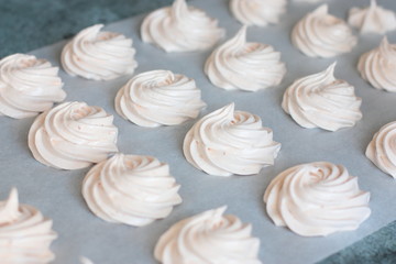 Many fresh (just made) marshmallow roses (zephyrs) in lines on cooking paper