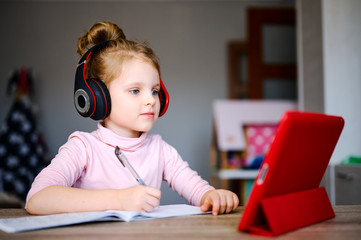 Distance learning online education. Schoolgirl in headphones studying at home with digital tablet...