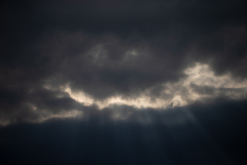 Dark sky with clouds and rays of the sun. Background cloudy day.