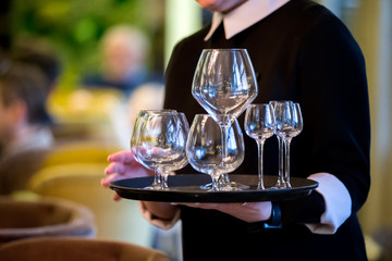 Hands hold a tray with glasses. Waiter in a restaurant.