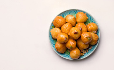 lokma is a sweet dessert in the middle east. Sauteed lean balls in a plate on a white background. Copy space