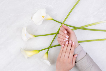 Woman hands with beautiful colored nails above flowers in the background