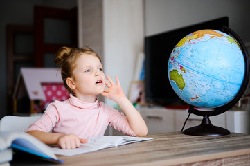 Cute little caucasian preschool girl doing homework. Child reading books and learning at home. Distance education