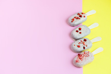 Ice cream on stick coated with white chocolate and red sprinkles of strawberry . Yellow and pink background. Copy spa?e. Summer food concept