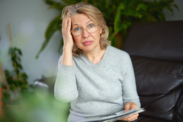 Shocked,woman reading newspaper bad news