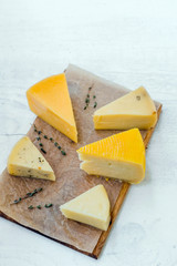 different fresh cheese on wooden cutting board. top view