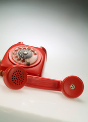 A a red vintage old rotary phone with handset picked up.