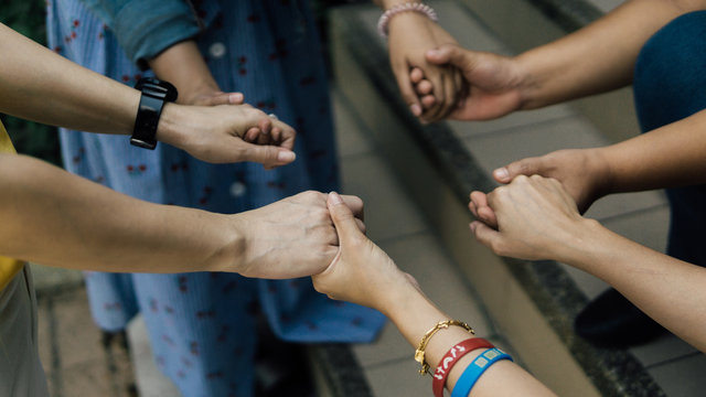 Group of christian are holding hands and pray together outdoor.