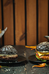 Two black burger on dark wooden texture background