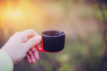 female hand holds a thermos cup with hot tea or coffee 