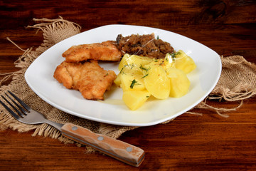 breaded chicken breast with boiled potatoes and fried cabbage