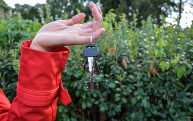 Female hand with bunch of house keys on a ring hanging on the finger. Concept of moving in new...