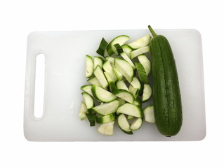 Zucchini cut into pieces on a white plastic cutting board Isolated on a white background.