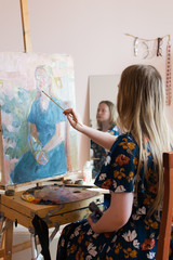 teen girl at home paints, looking in the mirror