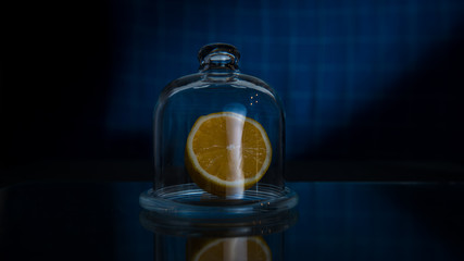 Half lemon in a glass lemon storage container on a dark blue background