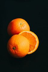 Vertical poster photo of an orange on a black background with light coming