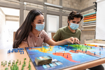 Fototapeta premium Group of youths with face masks playing a board game.