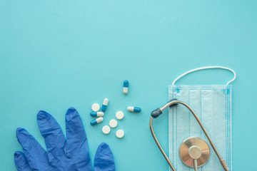 Pharmaceutical medicine tablets and stethoscope on a blue background. Face mask, surgical mask. The concept of medicine, hygiene and healthcare. Coronavirus. top view, copy space. Flu season.