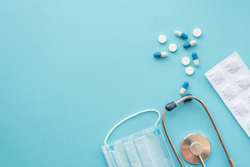 Fototapeta na wymiar Pharmaceutical medicine tablets and stethoscope on a blue background. Face mask, surgical mask. The concept of medicine, hygiene and healthcare. Coronavirus. top view, copy space. Flu season.