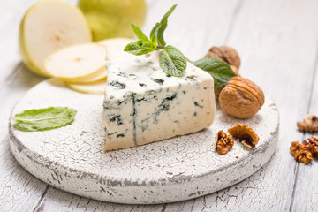 Segment of blue mould cheese - Gorgonzola with pear and walnuts on wooden board.  Top view