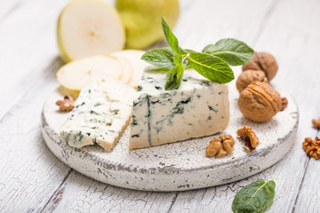 Segment of blue mould cheese - Gorgonzola with pear and walnuts on wooden board.  Top view