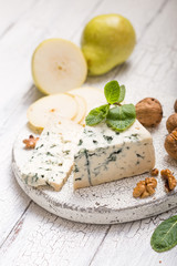 Segment of blue mould cheese - Gorgonzola with pear and walnuts on wooden board.  Top view