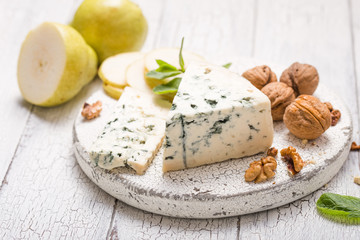 Segment of blue mould cheese - Gorgonzola with pear and walnuts on wooden board.  Top view