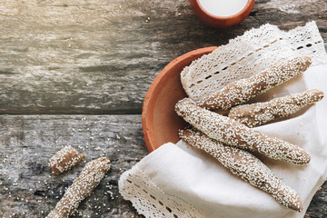 freshly baked fresh homemade breadsticks with sesame on clay plate with milk on a wooden table. Country food. Rustic style. top view.