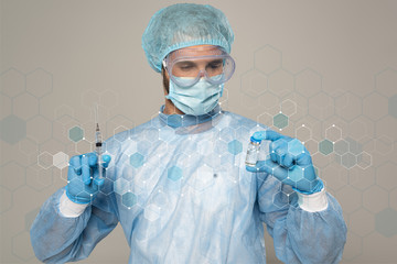 Doctor in medical mask and protective googles holding jar of vaccine and syringe isolated on grey,...