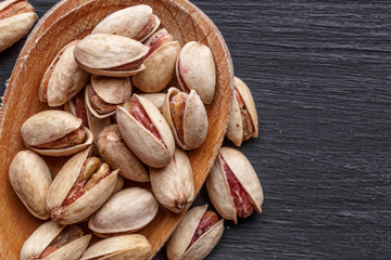 Pistachios nuts on dark background, top view, healthy snack. Space for text