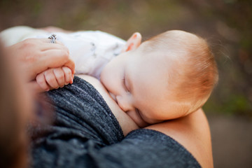 Close-up of baby boy breastfeeding outdoors