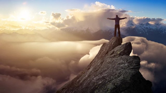 Cinemagraph Continuous Loop Animation. Adventurous Man Hiker With Hands Up on top of a Steep Rocky Cliff. Sunset or Sunrise. Landscape Taken from British Columbia, Canada. Concept: Adventure, Explore
