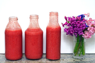 Glass bottles filled with colorful fresh homemade strawberry smoothies