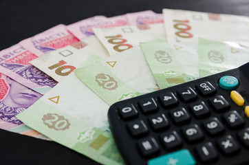 different hryvnias and calculator on a black background. A lot of Ukrainian money.