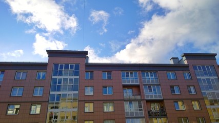 Facade of a new multi-story residential building. Blue sky with clouds. Sale and rental of economy class apartments. Comfortable housing. City living. Real estate. Stay at home concept. Be safe.