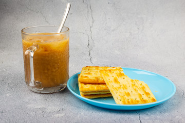 Cup of cold coffee with Crackers on a plate on wooden background.