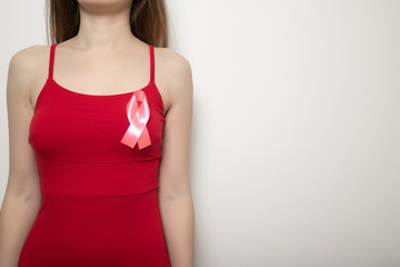 The symbol of the fight against breast cancer. Pink ribbon on the girl’s chest. Health and medical concept. Place for text