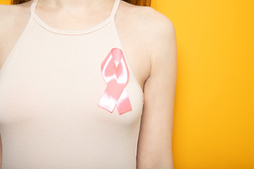 The symbol of the fight against breast cancer. Pink ribbon on the girl’s chest.