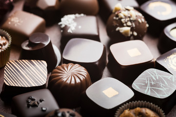 Mixed luxury dark and milk chocolate truffles. Assorted delicious handmade chocolate pralines in a row. Full frame background. Studio shot. Close-up