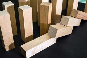 Falling wooden blocks on a black background. Close-up. Crisis and failure in Business, Insurance and Risk Management Concept.