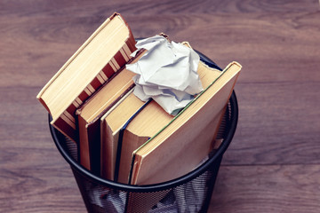 Books and crumpled paper in the bin. Books that do not read, low-grade literature