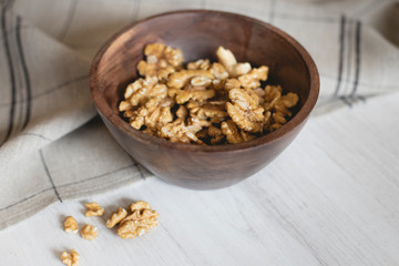Wooden bowl full of walnuts on a grey napkin.